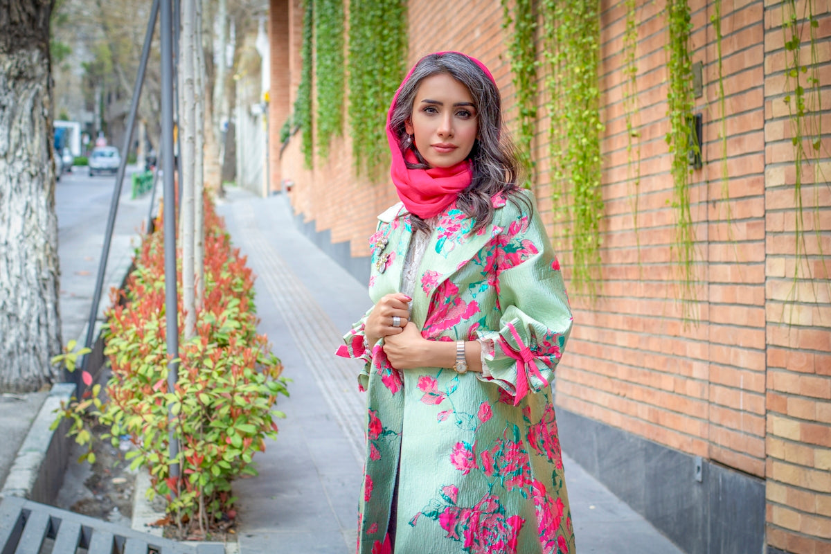 woman in white and red floral dress standing on sidewalk during daytime