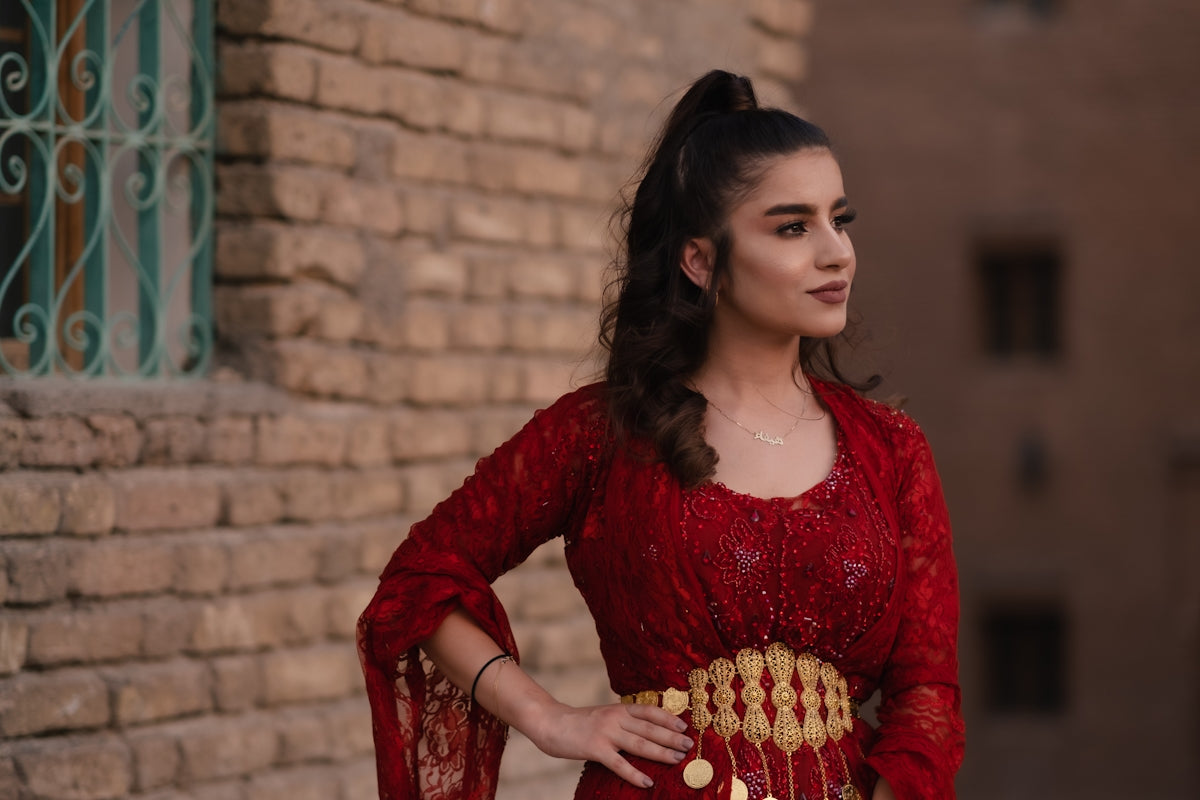 a woman in a red dress standing in front of a brick wall