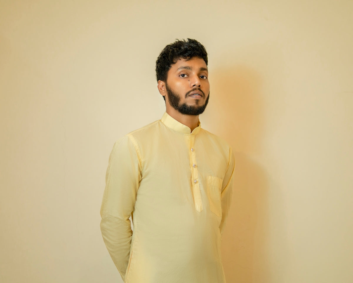 a man standing in front of a wall wearing a yellow shirt