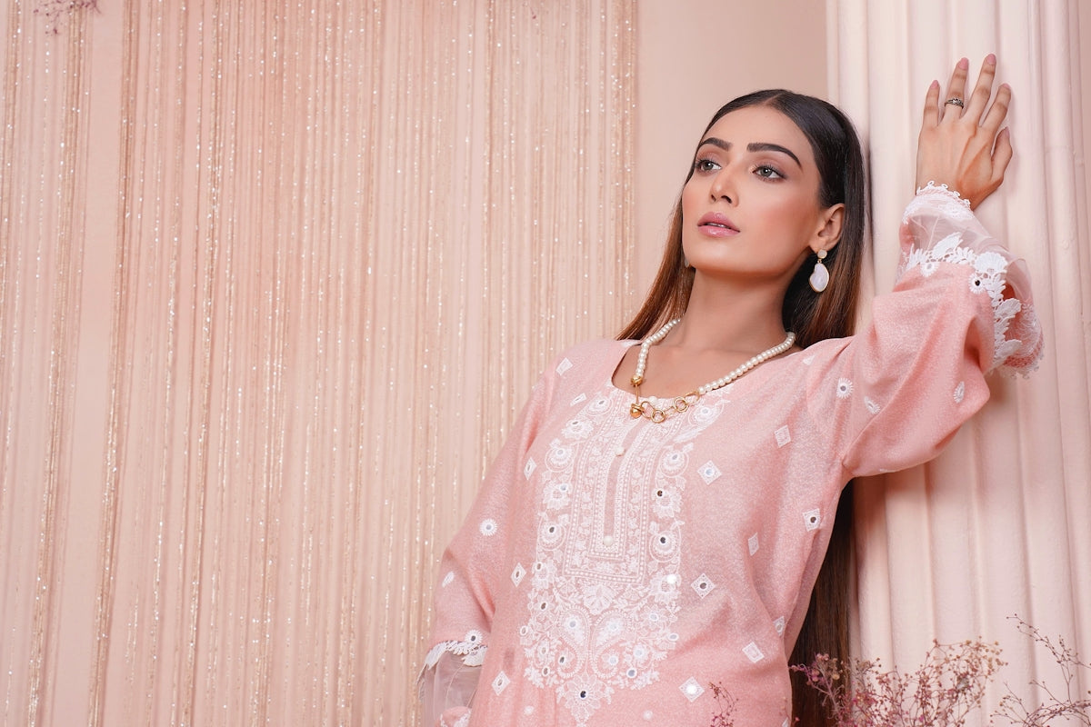 a woman in a pink outfit leaning against a wall