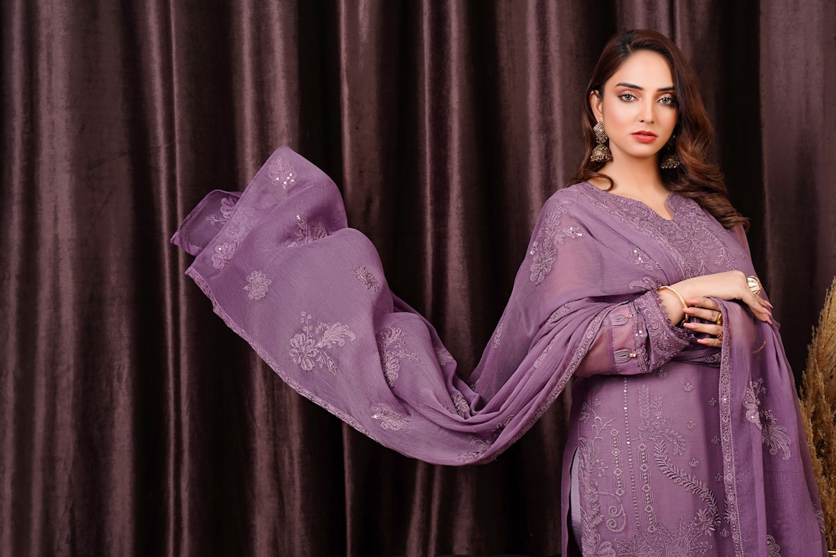 a woman in a purple dress standing in front of a curtain