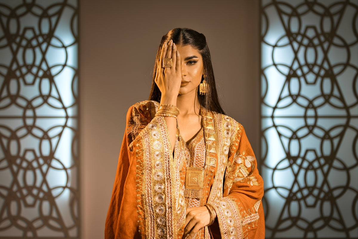 Woman in ornate clothing covering one eye