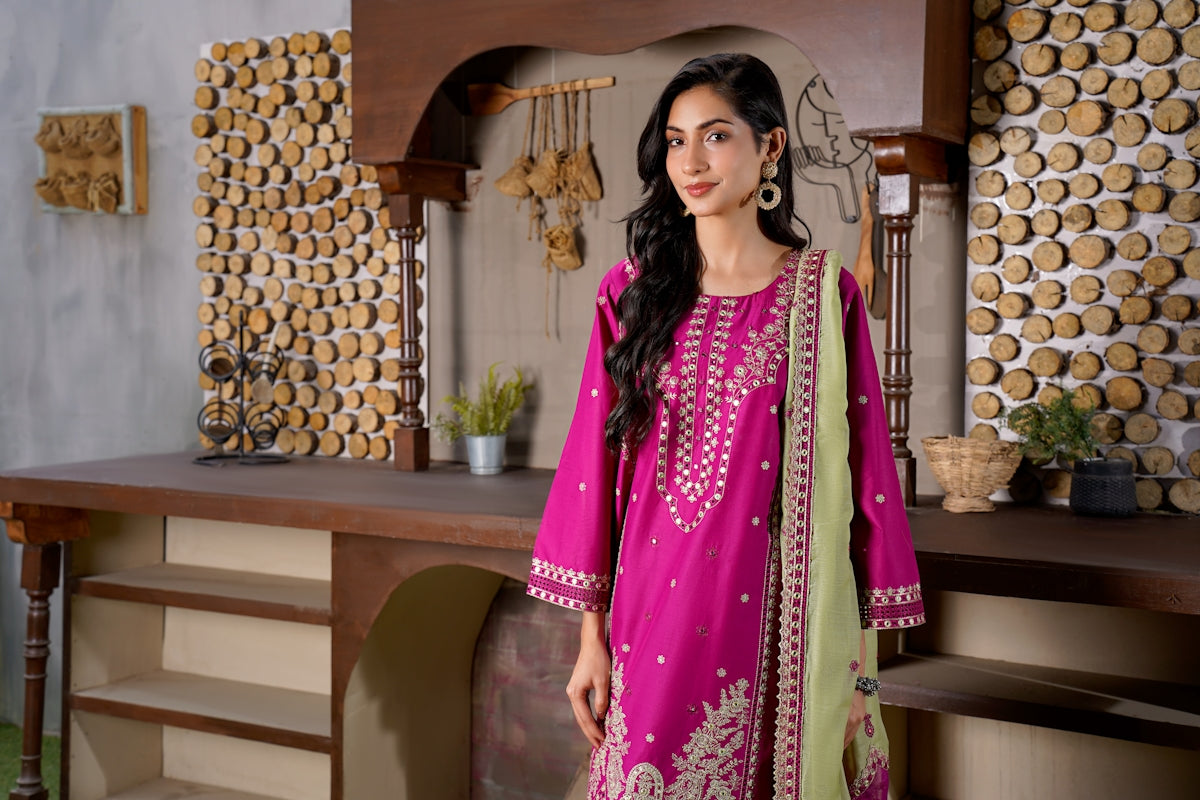 Woman in a vibrant pink embroidered dress stands indoors.