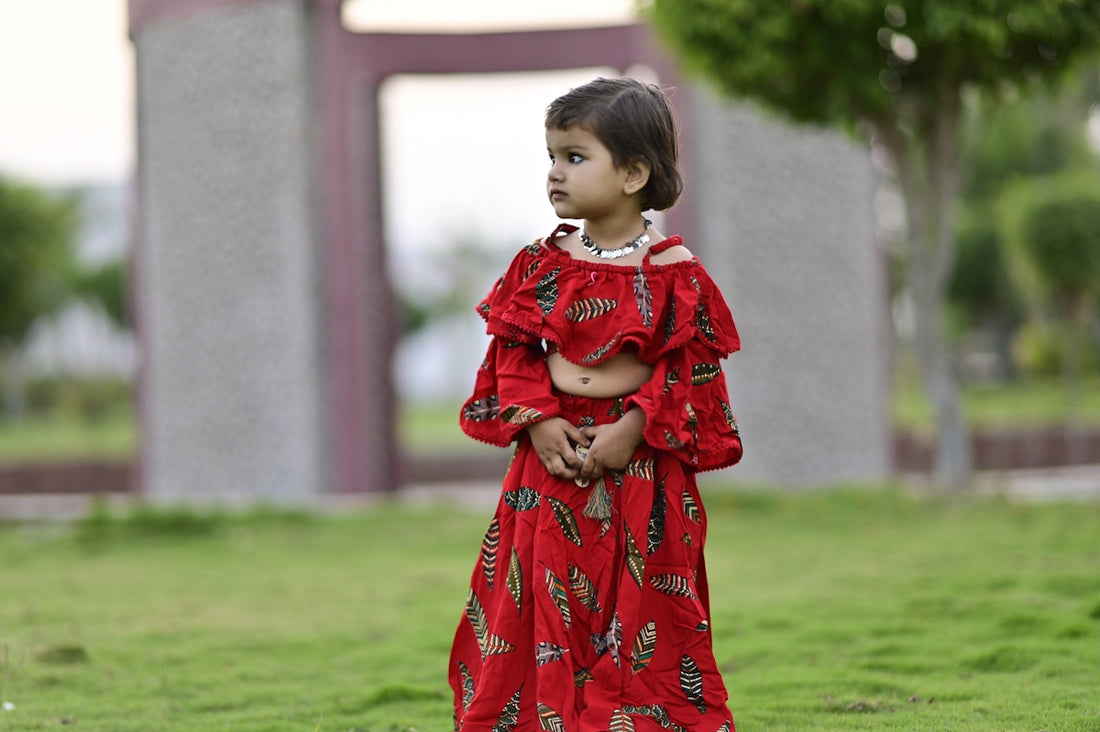 girl in red and white long sleeve dress standing on green grass field during daytime