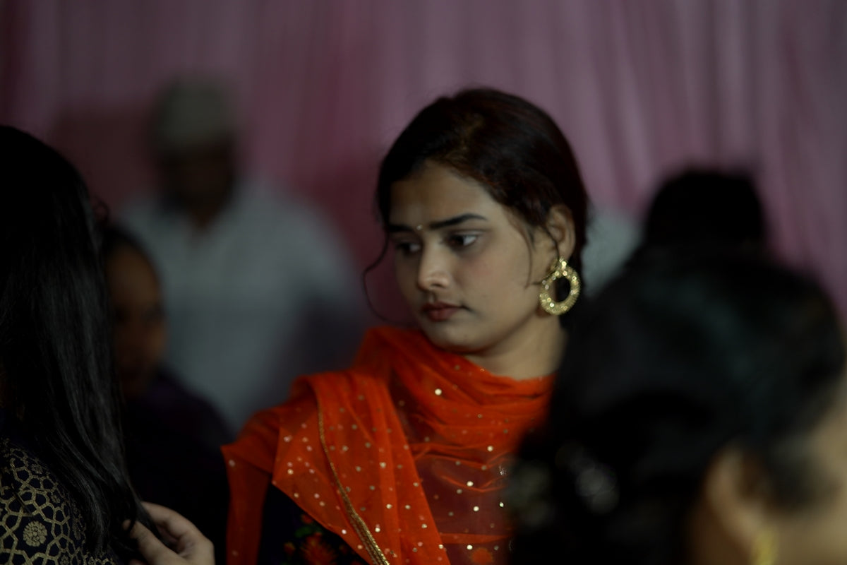 a woman in an orange sari and gold earrings