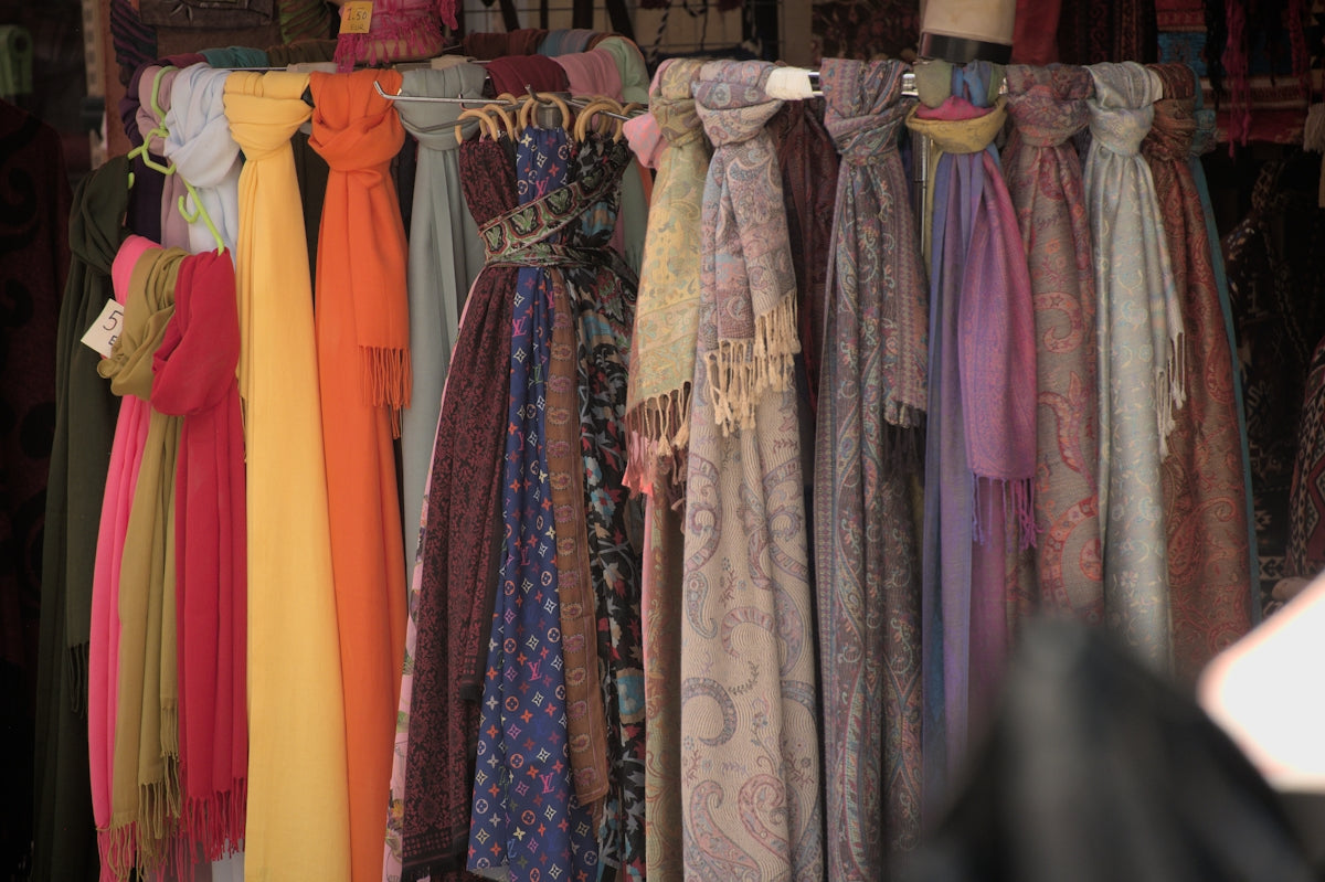 a rack of scarves and dresses hanging on a rack