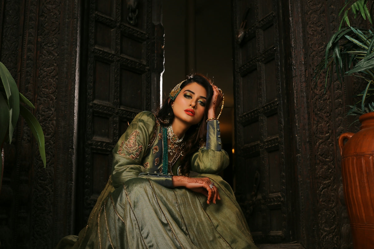 A woman in a green dress sitting in a doorway