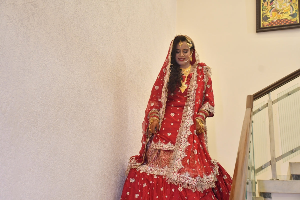 A bride in a red dress posing on stairs.