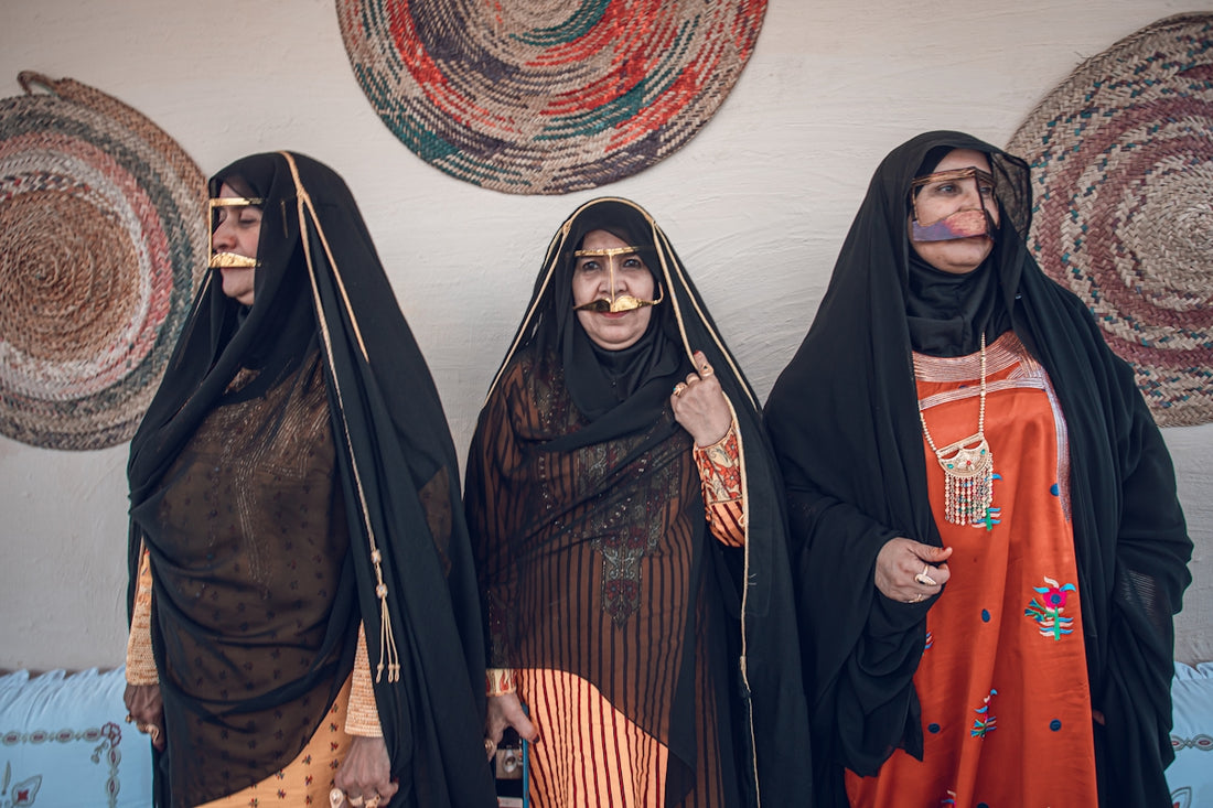 Three women in traditional attire stand together.
