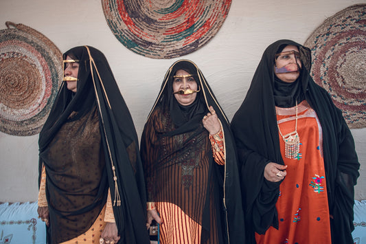 Three women in traditional attire stand together.