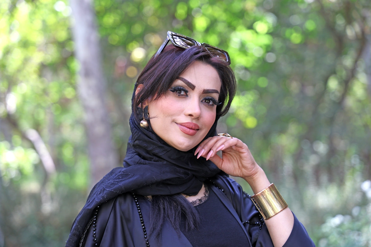 A woman with dark hair and a black headscarf smiles.